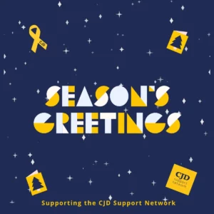 A christmas card with a navy background. It says 'Season's Greetings' and features the CJD Support Network logo and yellow remembrance/awareness ribbon.